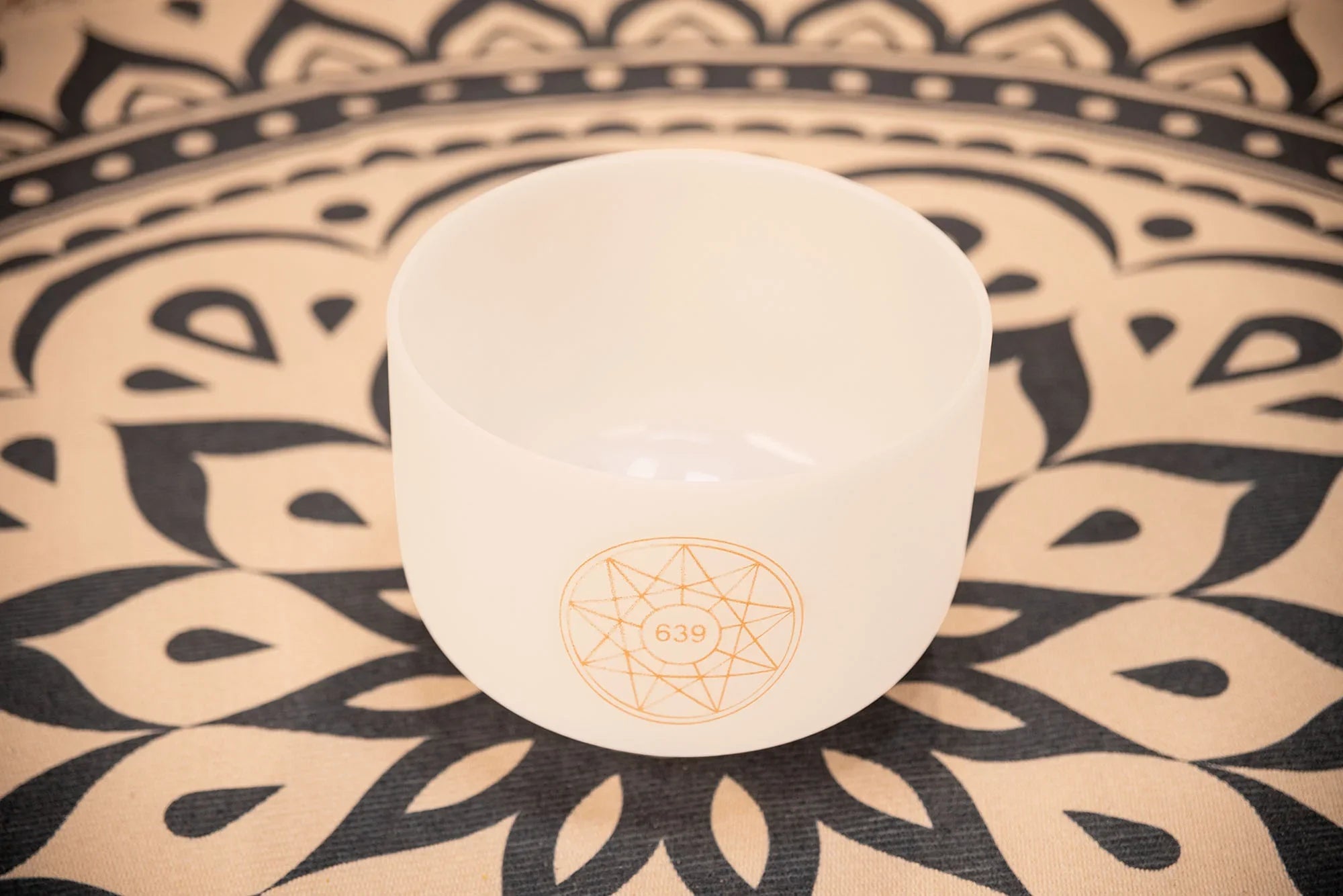 White crystal singing bowl with 639 Hz symbol on mandala-patterned mat