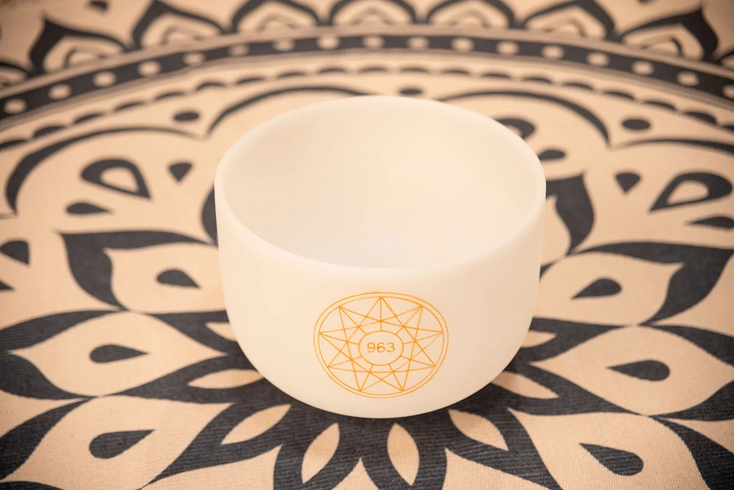 White crystal singing bowl with 963 symbol on patterned mandala cloth for sound healing