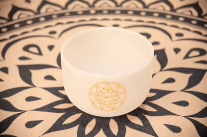 White crystal singing bowl with 963 symbol on patterned mandala cloth for sound healing