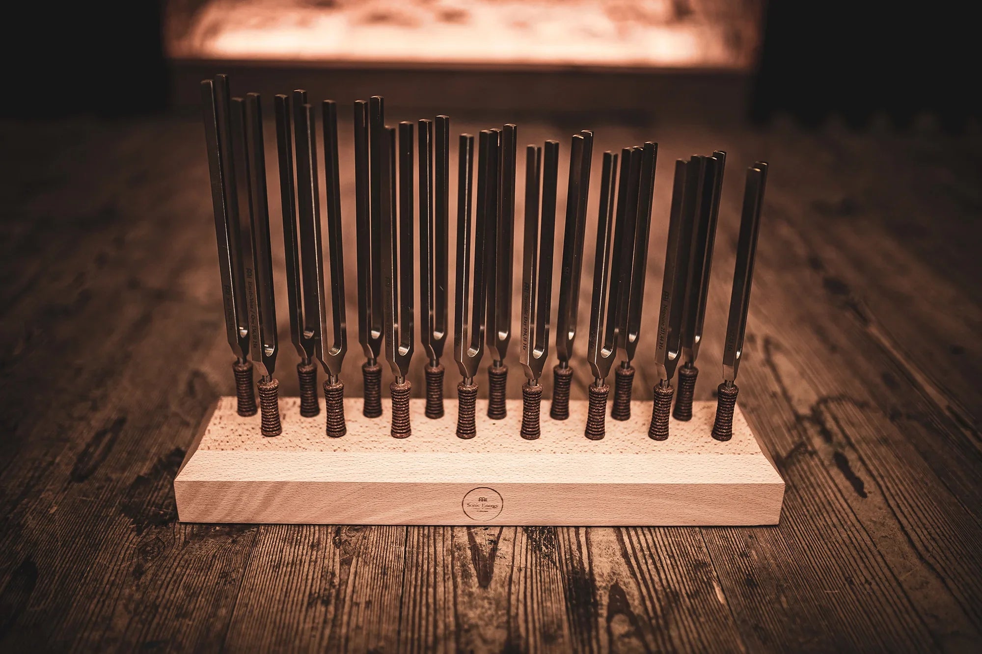 Set of tuning forks in a wooden holder on a rustic wooden surface, sound healing tools