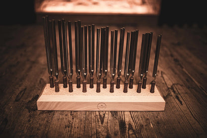 Set of tuning forks in a wooden holder on a rustic wooden surface, sound healing tools
