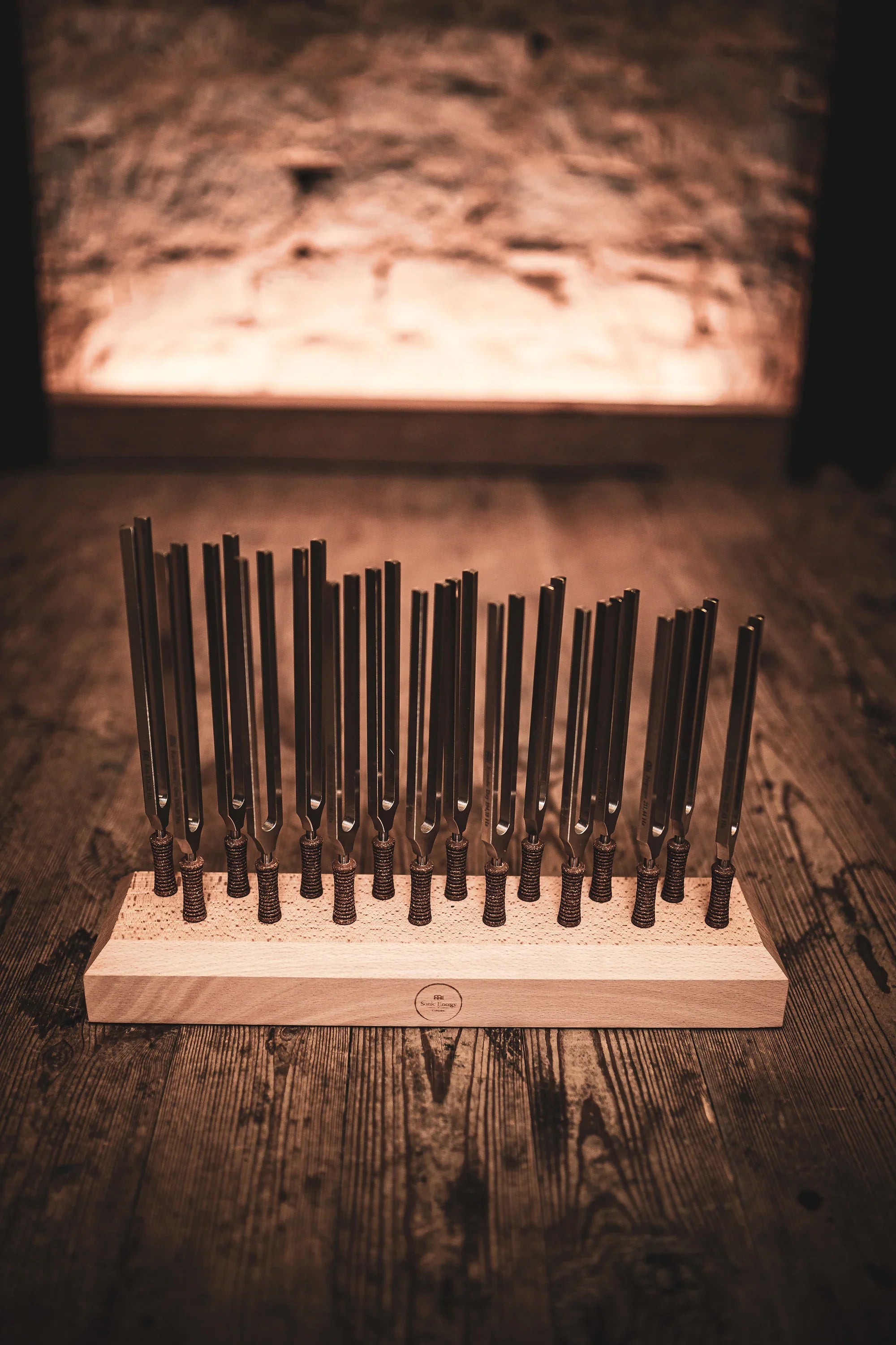 Set of tuning forks on a wooden base for sound healing, displayed on a rustic wood floor