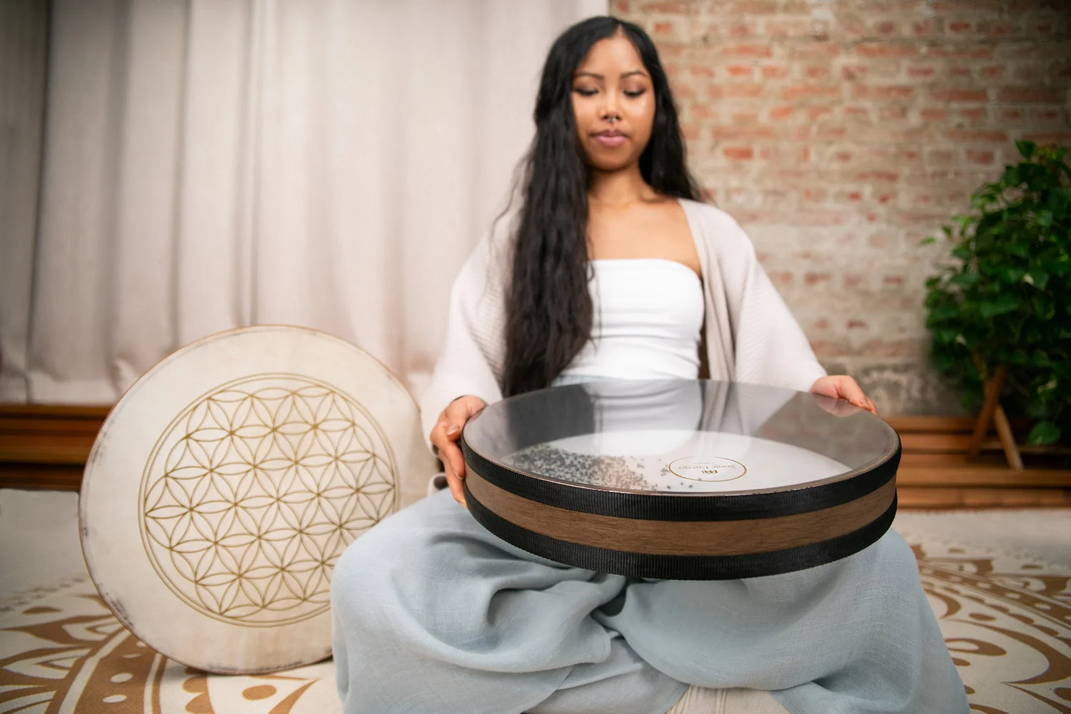Woman holding energy healing drum and monochord in serene meditation space