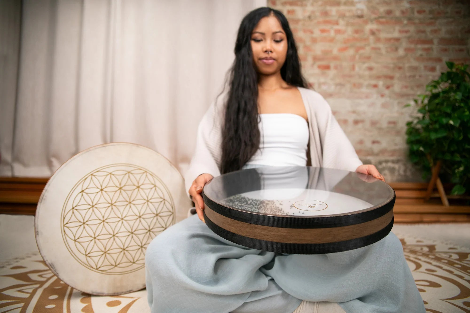 Woman holding energy healing drum and monochord in serene meditation space