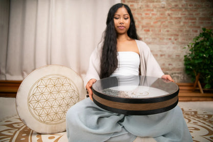 Woman holding energy healing drum and monochord in serene meditation space